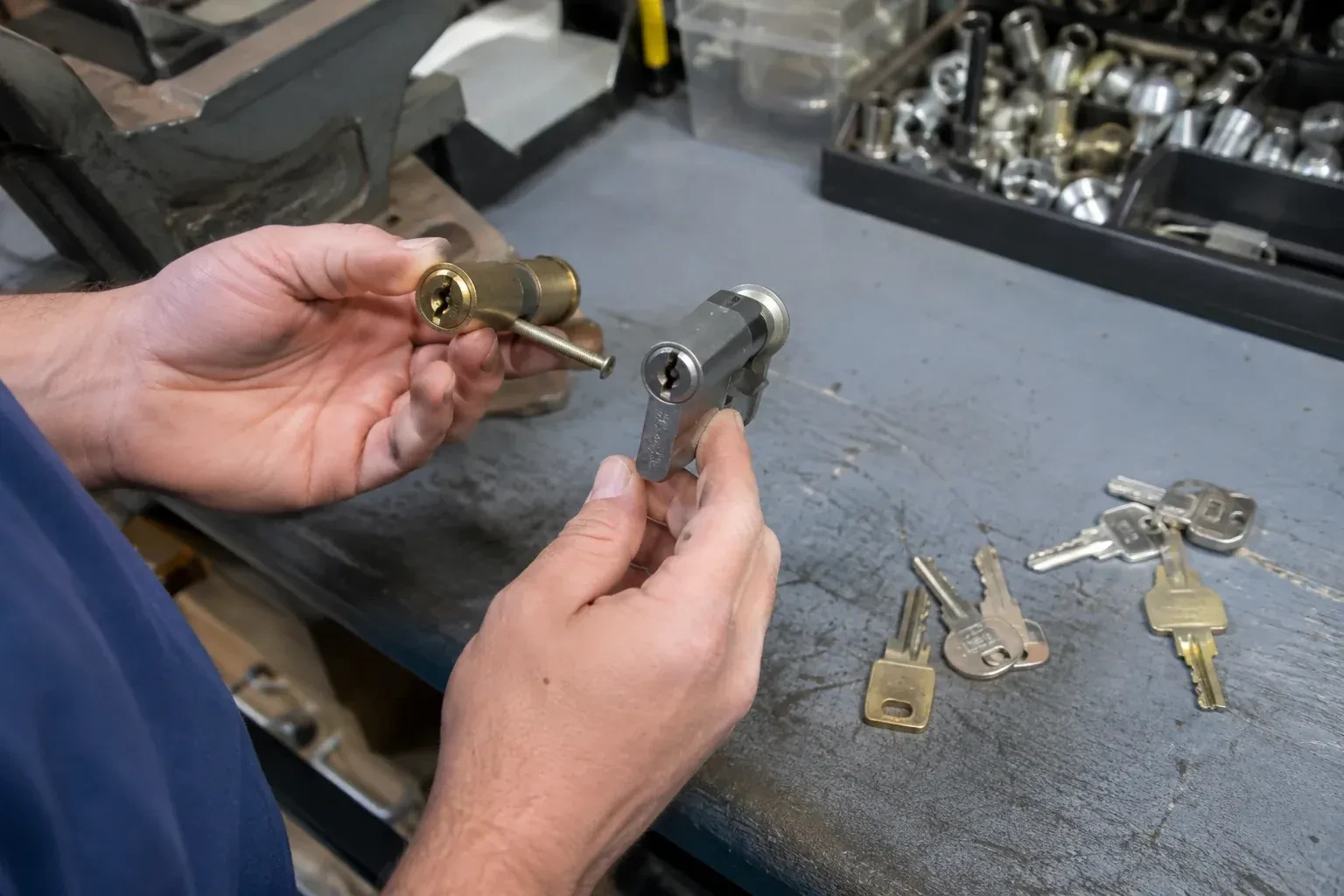 Hands comparing detached lock cylinders beside loose keys on a workbench. — Broken Key Extraction, Aurora